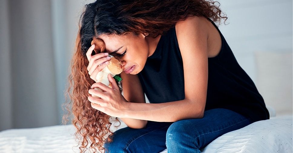 Mulher chora e abraça um brinquedo, ilustrando como superar a morte de um animal de estimação.